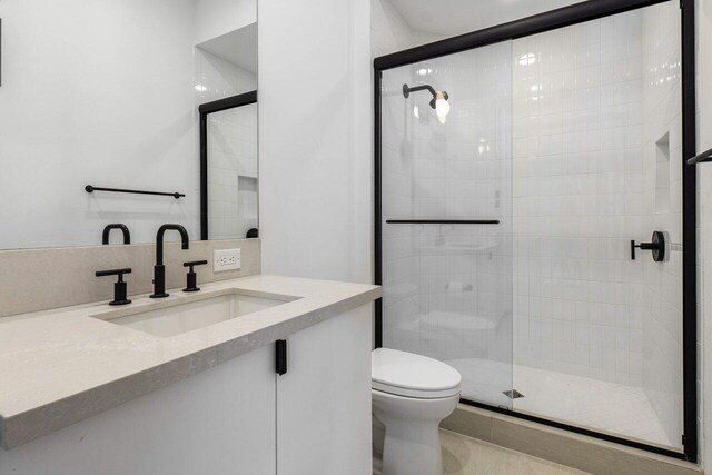 bathroom featuring vanity, toilet, and a shower with shower door