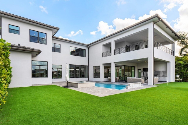 rear view of house featuring an outdoor kitchen, a pool with hot tub, a patio, and a lawn