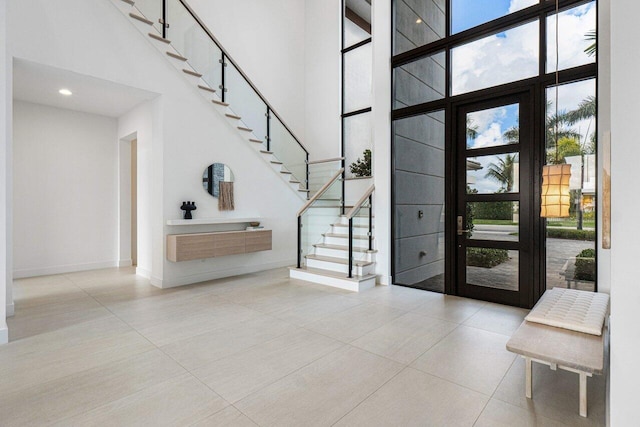 tiled foyer entrance featuring floor to ceiling windows and a towering ceiling