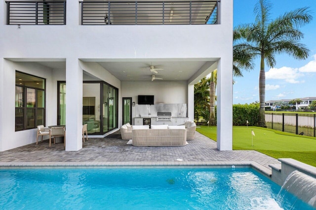 view of pool featuring pool water feature, a patio area, outdoor lounge area, ceiling fan, and exterior kitchen