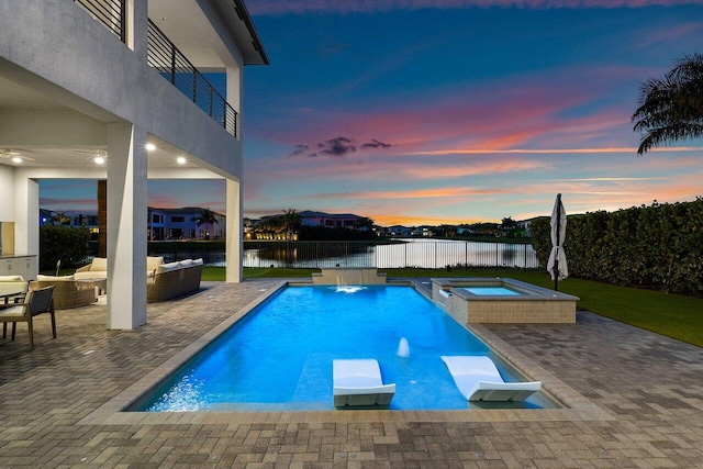 pool at dusk with a water view, an outdoor living space, an in ground hot tub, and a patio area