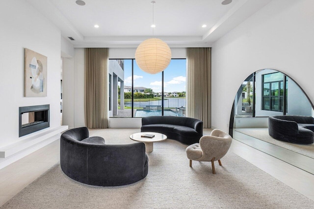 living room with a tray ceiling and tile patterned floors