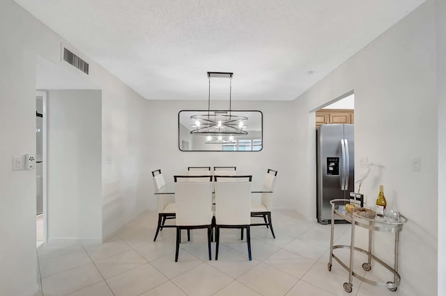 dining space featuring light tile patterned flooring, a chandelier, and a textured ceiling