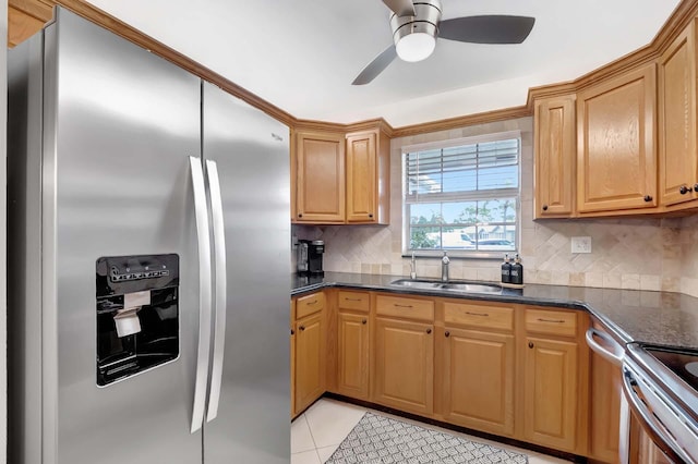 kitchen featuring sink, ceiling fan, appliances with stainless steel finishes, light tile patterned flooring, and dark stone counters