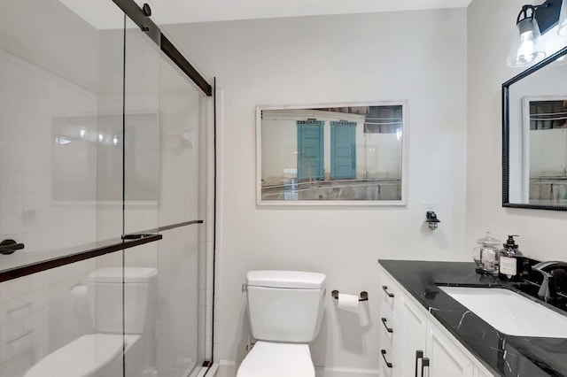 bathroom featuring vanity, a shower with door, and toilet