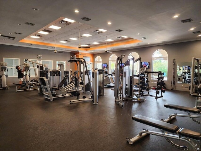 workout area with a raised ceiling and crown molding