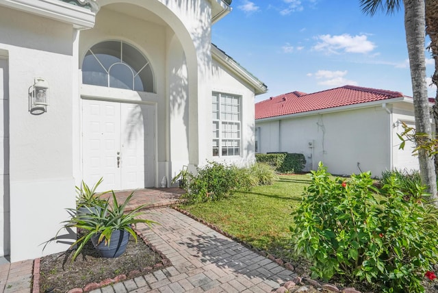 view of exterior entry with a lawn