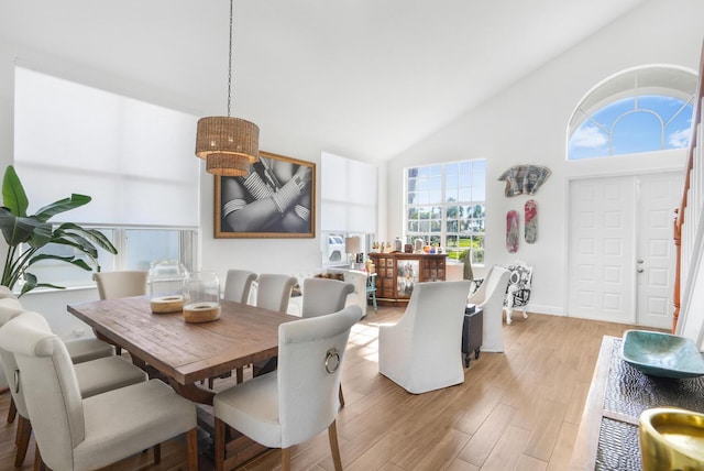 dining room with high vaulted ceiling and light hardwood / wood-style floors