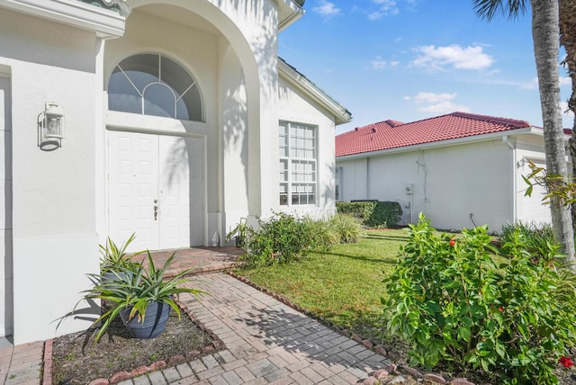 4209 Bahia Isle Cir, Wellington, FL 33449 - view of exterior entry featuring stucco siding, a yard, and a tile roof