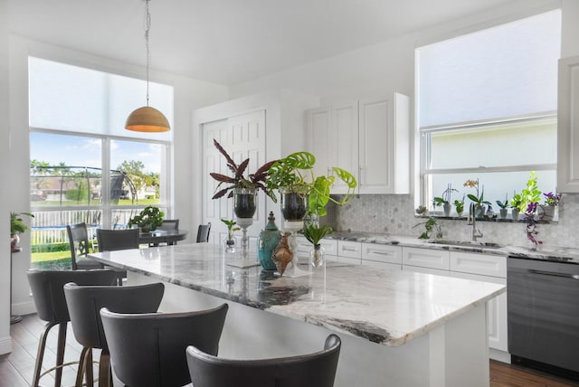 kitchen featuring white cabinetry, hanging light fixtures, dishwasher, and a kitchen island