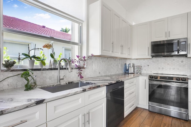 kitchen featuring dark hardwood / wood-style floors, sink, white cabinets, light stone counters, and stainless steel appliances