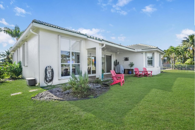 back of property featuring a yard and ceiling fan