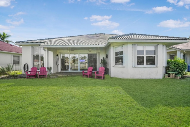 back of property with a yard and ceiling fan