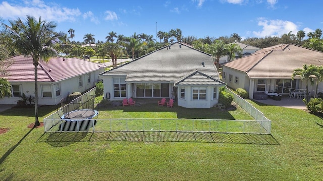 4209 Bahia Isle Cir, Wellington, FL 33449 - rear view of property with a lawn, a fenced backyard, a trampoline, and a tiled roof