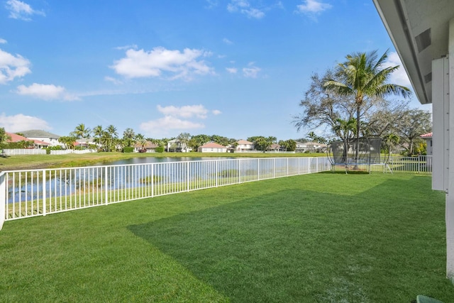 view of yard with a trampoline and a water view