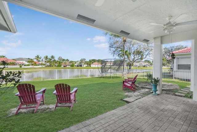 view of yard featuring a water view, a trampoline, ceiling fan, and a patio area