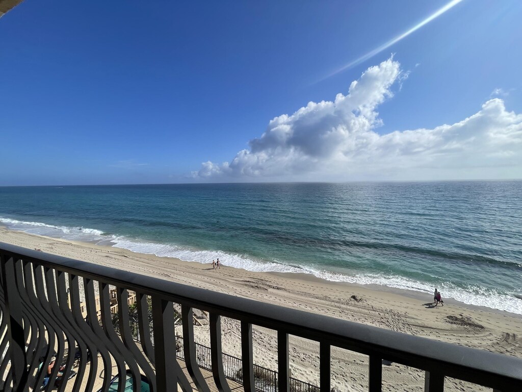 balcony featuring a water view and a beach view