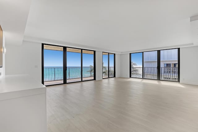 4000 S Ocean Blvd Unit 401, South Palm Beach, FL 33480 - unfurnished living room featuring expansive windows, light wood-type flooring, and a water view
