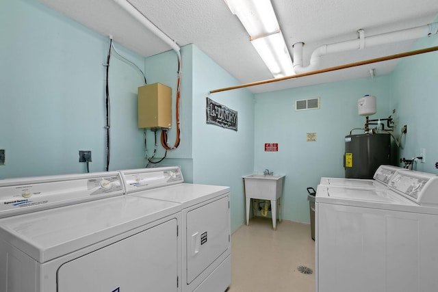 laundry area featuring water heater, sink, washer and dryer, and a textured ceiling