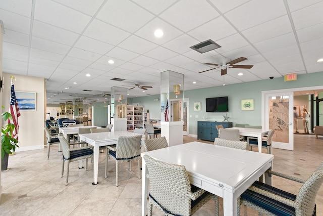 dining space with a paneled ceiling, light tile patterned floors, and ceiling fan