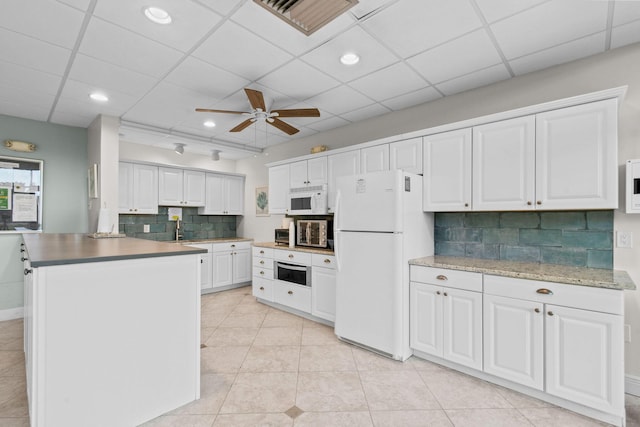 kitchen with white cabinetry, light tile patterned floors, ceiling fan, white appliances, and decorative backsplash