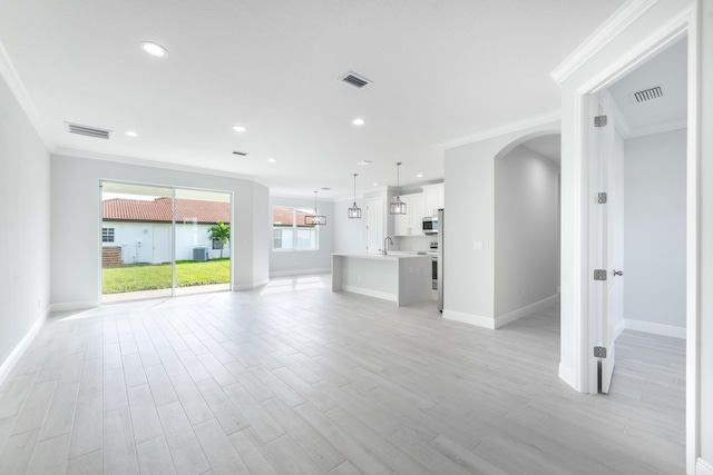 unfurnished living room with ornamental molding, sink, and light wood-type flooring