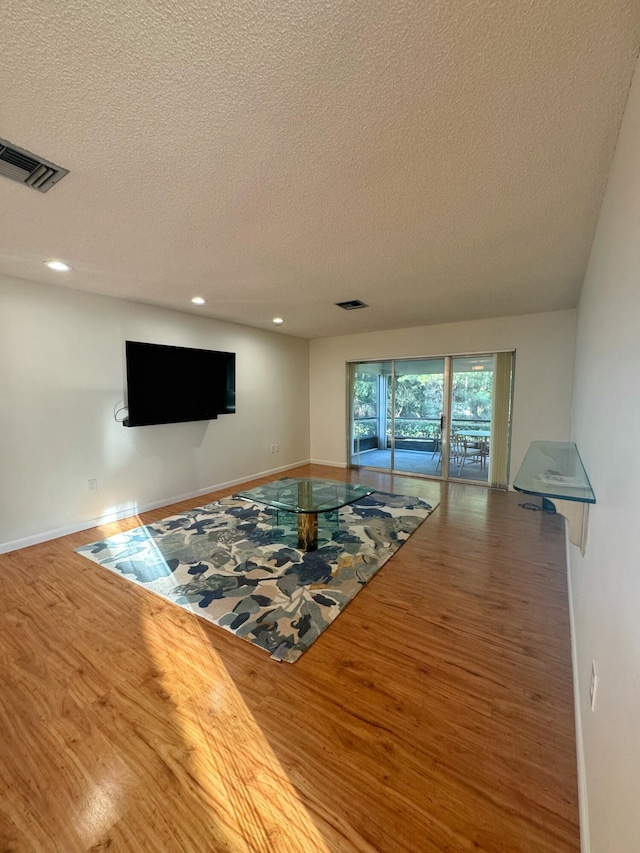 unfurnished living room with wood-type flooring and a textured ceiling