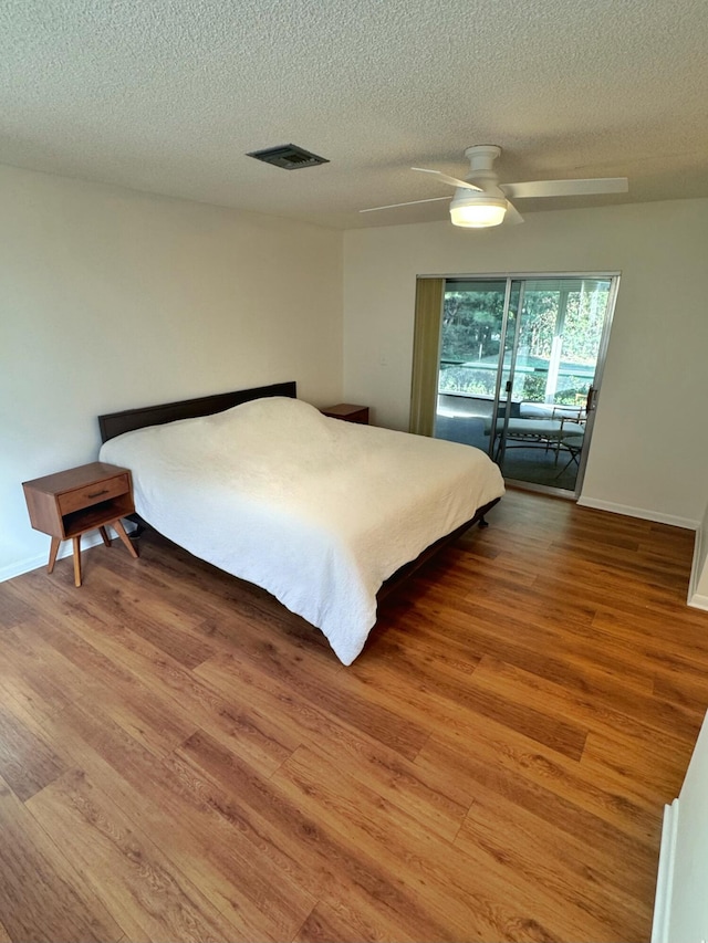 bedroom featuring ceiling fan, hardwood / wood-style floors, and a textured ceiling