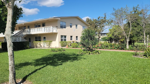 rear view of house featuring a balcony and a yard