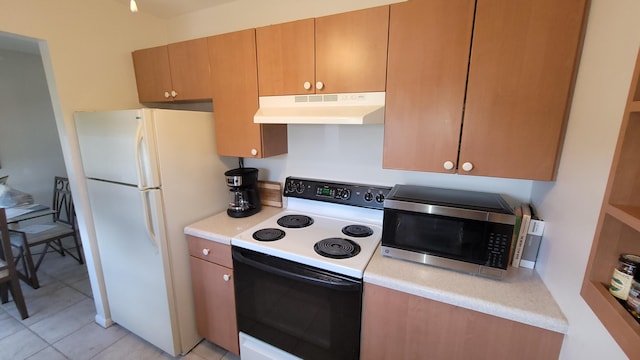 kitchen with range with electric cooktop, white fridge, and light tile patterned flooring