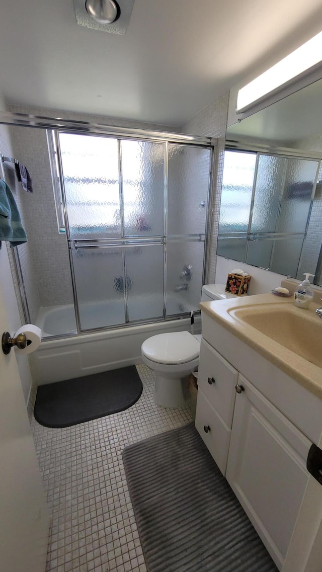 full bathroom featuring tile patterned flooring, vanity, shower / bath combination with glass door, and toilet