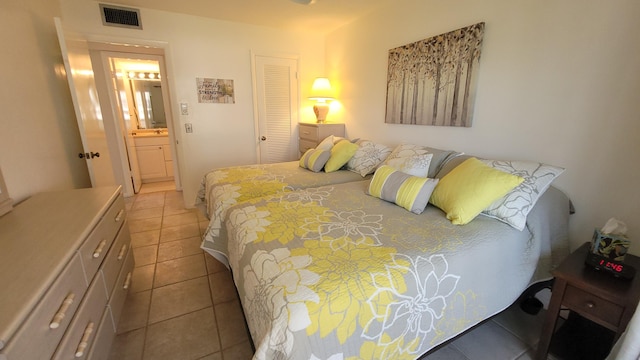 bedroom featuring ensuite bathroom, a closet, and light tile patterned floors