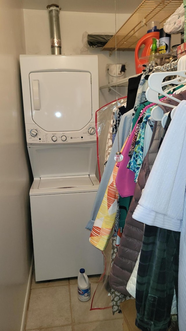 clothes washing area featuring light tile patterned floors and stacked washing maching and dryer