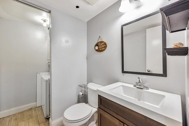 bathroom featuring hardwood / wood-style flooring, independent washer and dryer, vanity, and toilet