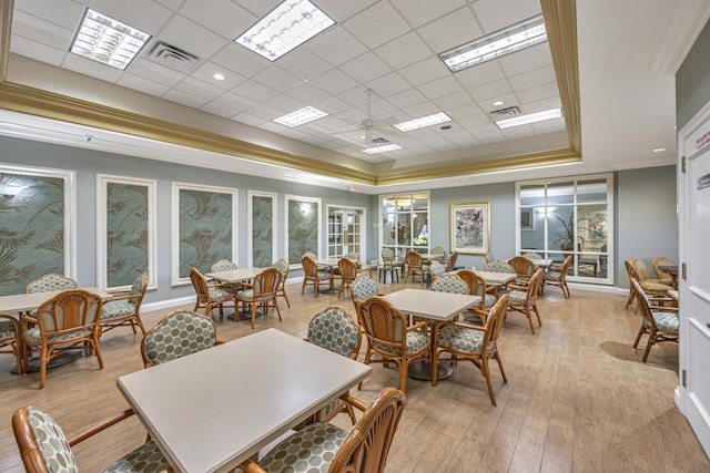 dining area featuring ornamental molding, a raised ceiling, ceiling fan, and light wood-type flooring