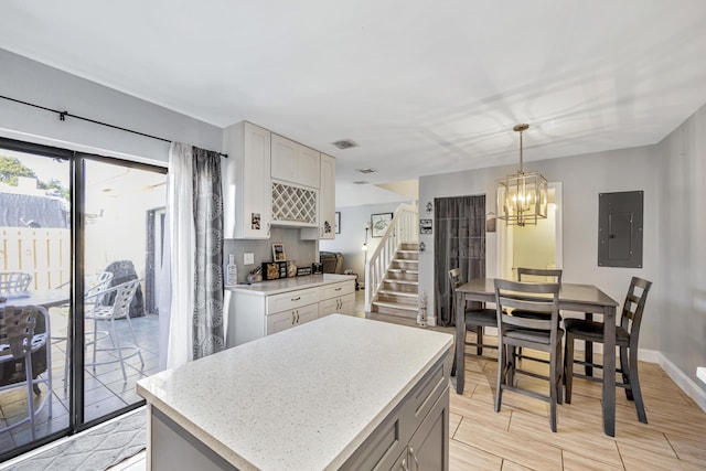 kitchen with pendant lighting, a chandelier, a center island, electric panel, and light hardwood / wood-style floors