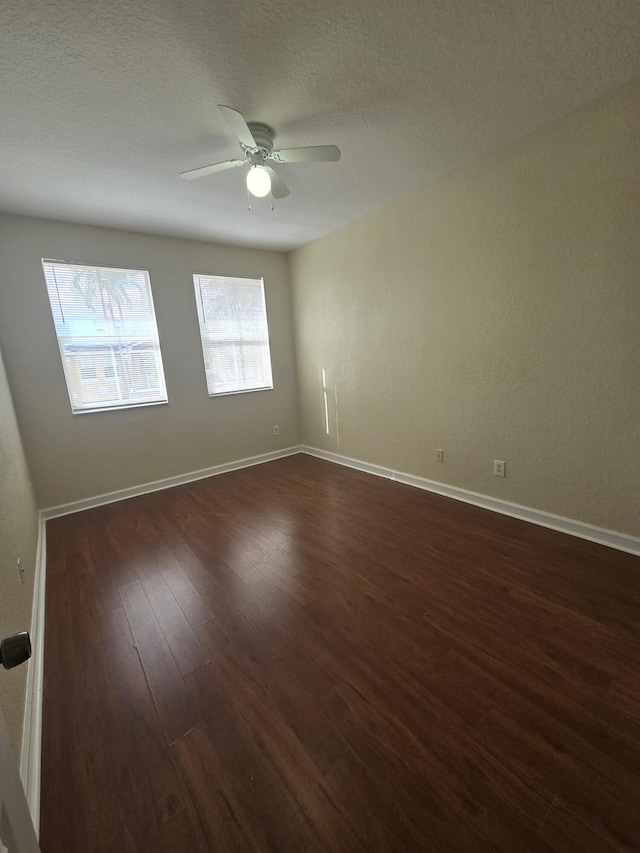 empty room featuring ceiling fan, a textured ceiling, and dark hardwood / wood-style flooring