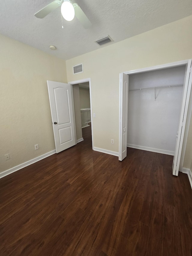 unfurnished bedroom featuring dark hardwood / wood-style flooring, a textured ceiling, ceiling fan, and a closet