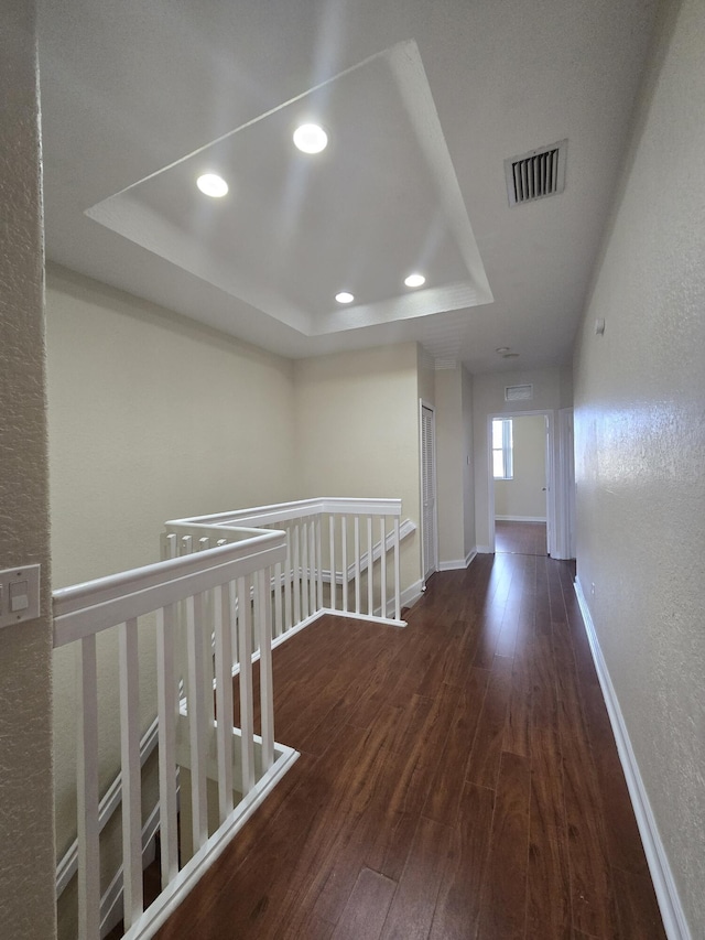 hallway featuring dark hardwood / wood-style floors and a raised ceiling