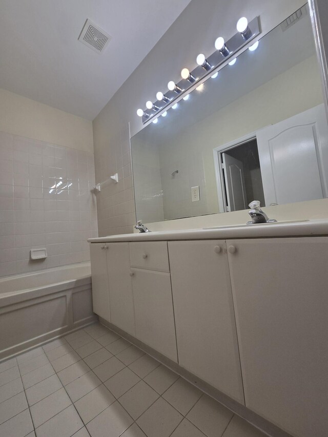 bathroom featuring tile patterned flooring, vanity, and tiled shower / bath combo