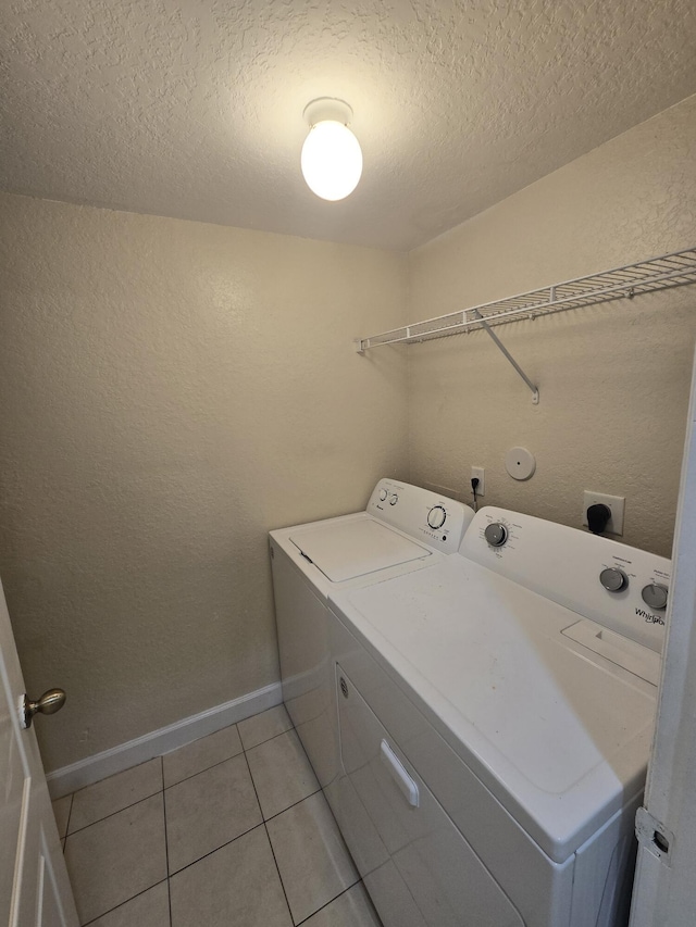 laundry area featuring light tile patterned floors, washing machine and clothes dryer, and a textured ceiling