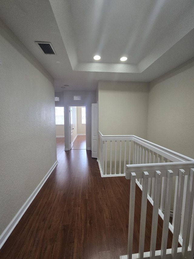 hall featuring a raised ceiling and dark hardwood / wood-style floors