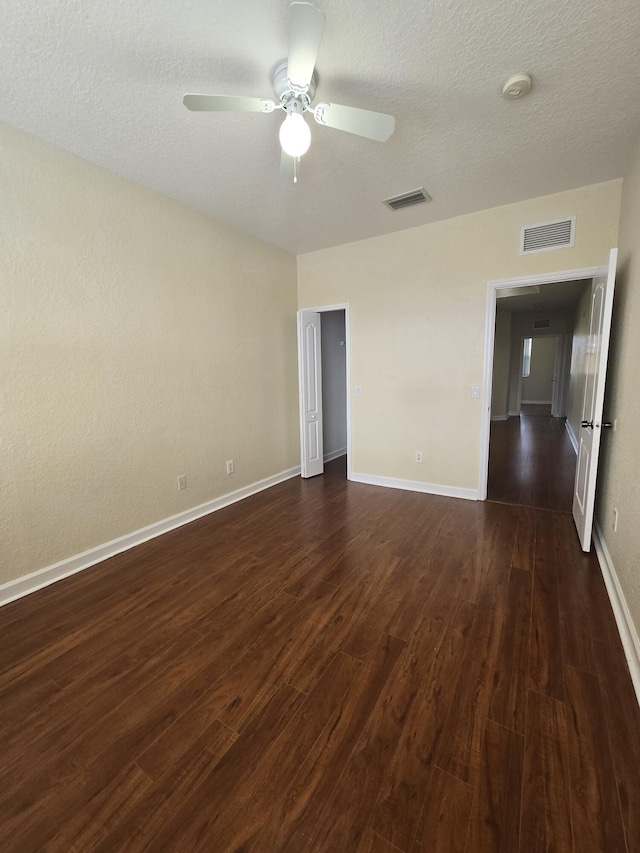 spare room featuring dark hardwood / wood-style flooring, a textured ceiling, and ceiling fan