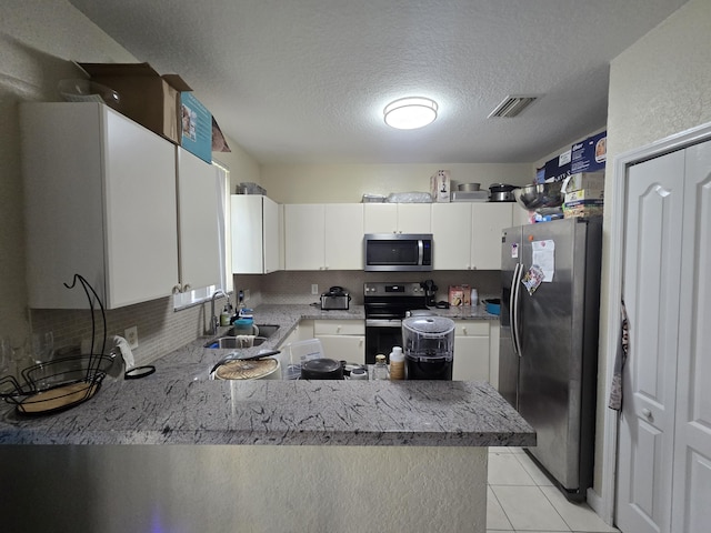 kitchen with sink, stainless steel appliances, a textured ceiling, white cabinets, and kitchen peninsula