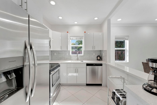 kitchen featuring sink, light tile patterned floors, appliances with stainless steel finishes, backsplash, and white cabinets