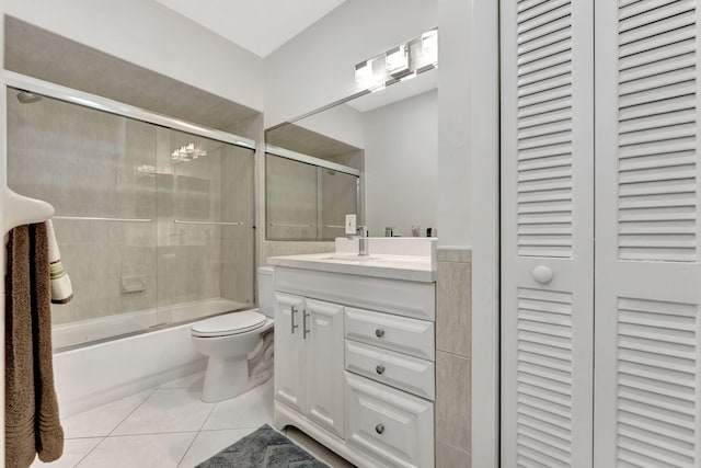 full bathroom featuring bath / shower combo with glass door, tile patterned floors, vanity, and toilet