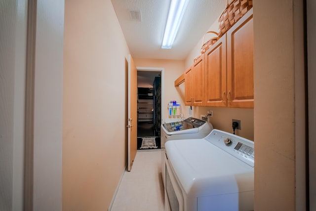 laundry room featuring cabinets, washer and dryer, and a textured ceiling