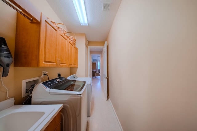 washroom featuring independent washer and dryer, sink, cabinets, and a textured ceiling