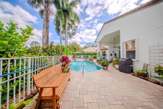 view of pool featuring ceiling fan, pool water feature, grilling area, and a patio area