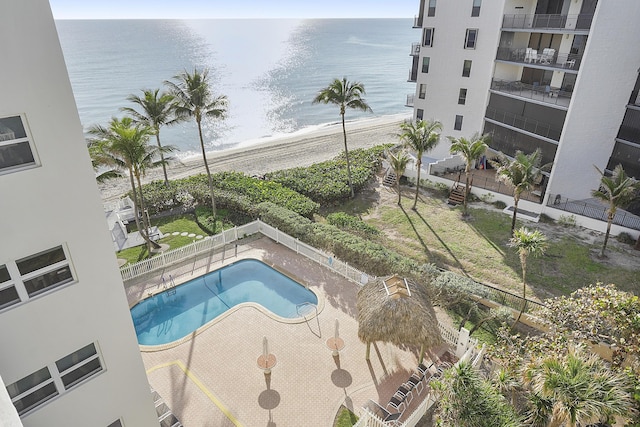 view of swimming pool featuring a view of the beach, a water view, and a patio area